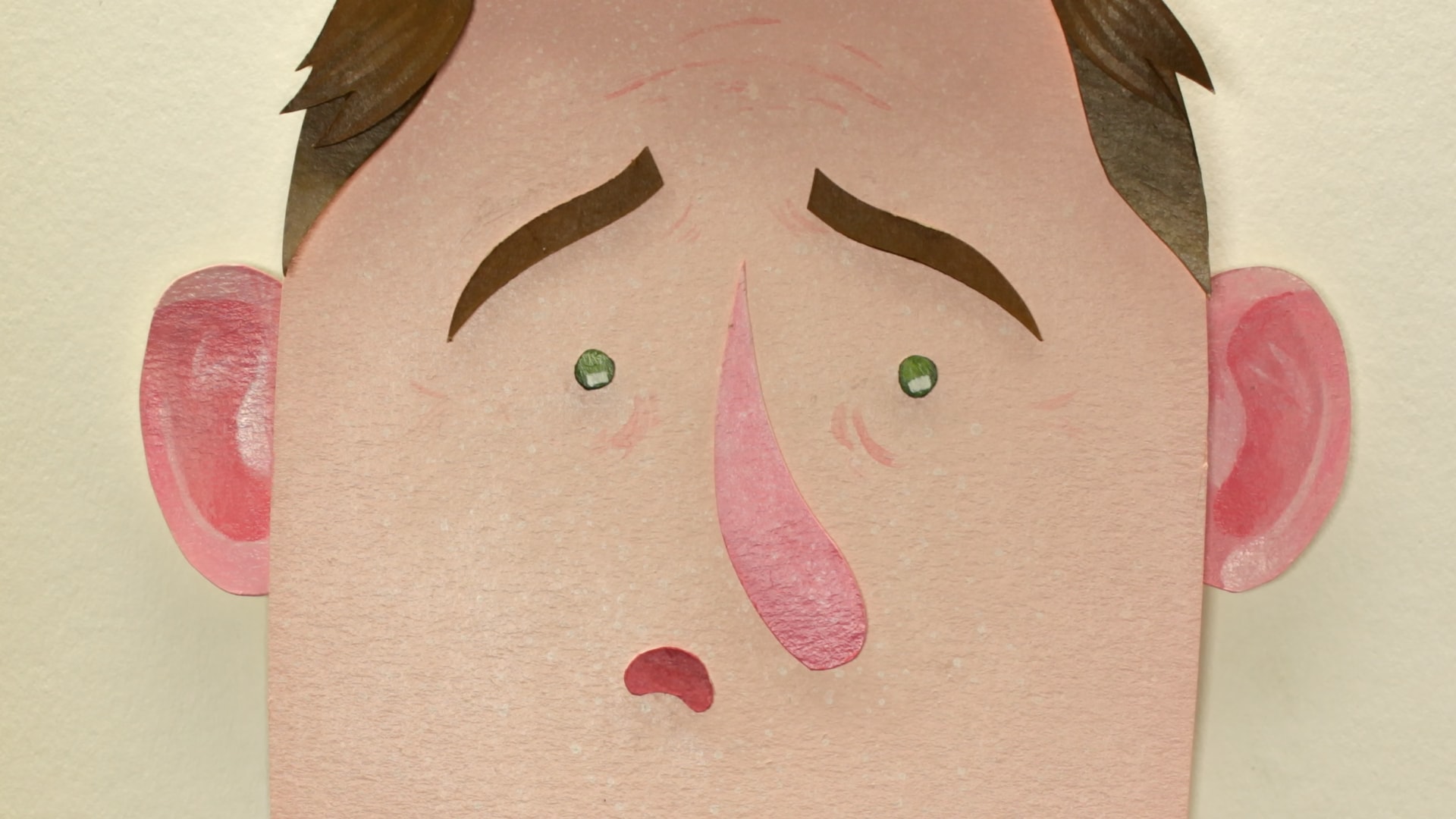 A close-up of an expressive paper character with rosy cheeks